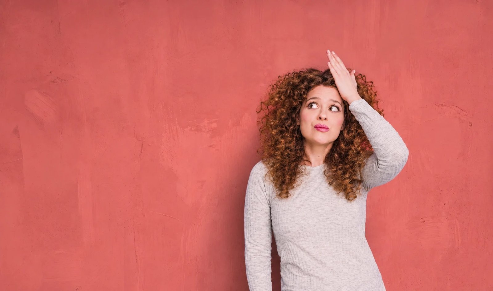 Young woman with her hand on her forehead, puzzled, trying to remember where she put something